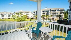 A balcony with white railings, a table, and two chairs. - Myrtlewood Retreat Near Golf & Ocean Breezes | Magnolia Pointe Luster Leaf 4890-205 (Myrtle Beach)