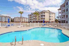 A swimming pool with a 5 ft depth marker, surrounded by lounge chairs and a white fence. - Myrtlewood Retreat Near Golf & Ocean Breezes | Magnolia Pointe Luster Leaf 4890-205 (Myrtle Beach)