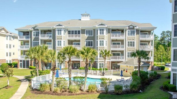 A multi-story hotel with balconies, a swimming pool, and palm trees. - Myrtlewood Retreat Near Golf & Ocean Breezes | Magnolia Pointe Luster Leaf 4890-205 (Myrtle Beach)