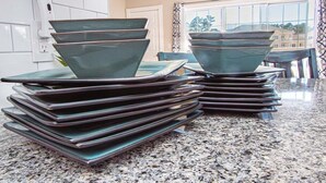 A kitchen with granite countertops and a stack of dark green ceramic plates.