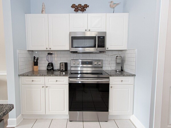 A kitchen with white cabinets, a stainless steel microwave, a toaster, and a coffee maker.