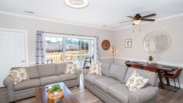 A living room with two grey sofas, a wooden coffee table, and a dining area with a table and chairs.