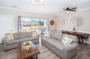 A living room with two grey sofas, a wooden coffee table, and a dining area with a table and chairs.