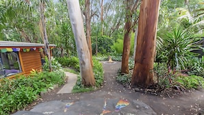 A garden pathway with colorful mosaic tiles leading to a wooden structure. - Peaceful, creative home in a lush
bush setting, only 300m from the beach! (Skenes Creek)