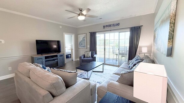 A living room with a television, sofas, a coffee table, and a ceiling fan.