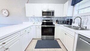 A modern kitchen with white cabinets, a microwave, a toaster, and a sink.