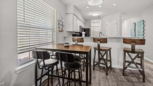 A modern kitchen with white cabinets, a black refrigerator, and a wooden island.