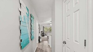 A hallway with white walls, a wooden floor, and a door at the end.