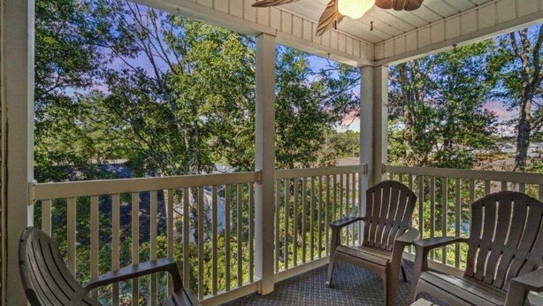 A covered porch with wooden chairs and a ceiling fan.