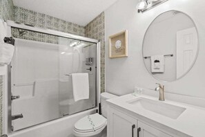 Un baño con cabina de ducha de vidrio, un lavabo blanco y un inodoro.