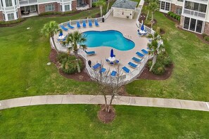 A circular pool with blue lounge chairs and palm trees, surrounded by a white fence. - Lake-view condo near Myrtlewood Golf in quiet area (Myrtle Beach)