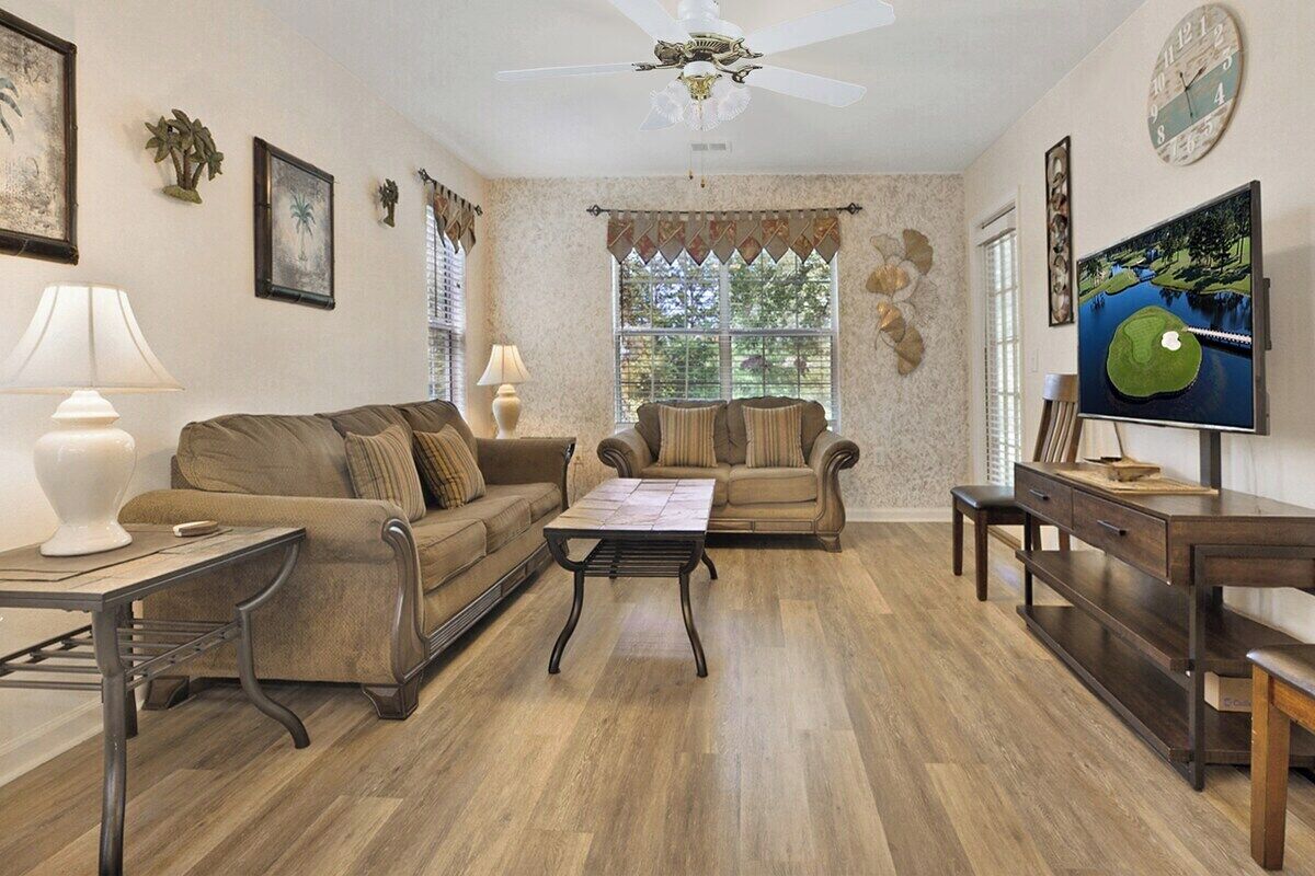 A living room with two sofas, a coffee table, a TV, and a desk.