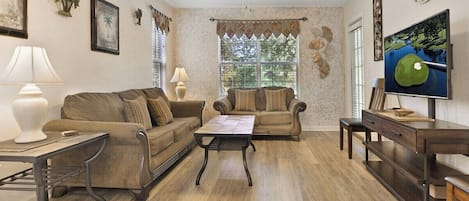 A living room with two sofas, a coffee table, a TV, and a desk.
