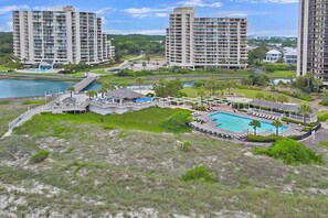 Un resort con varios edificios altos, una piscina y un puente que conecta diferentes zonas.