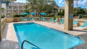 A swimming pool with lounge chairs and umbrellas, surrounded by a building with balconies. - Comfortable & Cozy 1Br Condo- Close to Beach! (Myrtle Beach)