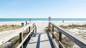 A wooden boardwalk leading to a beach with clear skies.