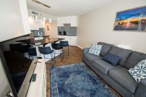 Una sala de estar moderna con un sofá gris, cojines estampados y una alfombra azul.