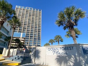 A building with a sign reading "Ocean Forest Plaza" and a palm tree in the foreground. - 2 level Oceanview Penthouse across from ocean! (Myrtle Beach)