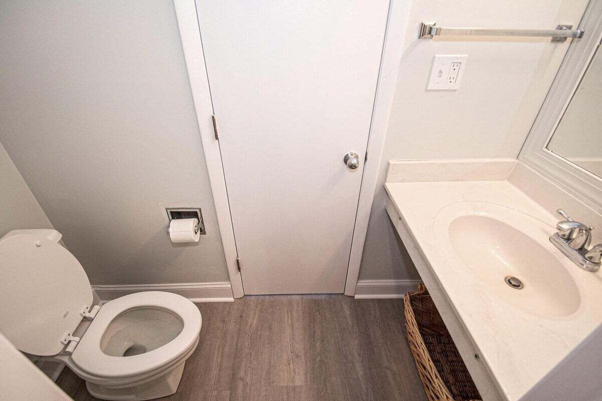 A bathroom with a toilet, sink, and a door.