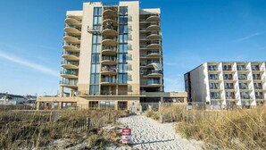 A beachfront hotel with multiple balconies, a sandy beach in front, and a private property sign.