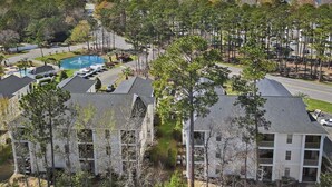Zona residencial con varios edificios de apartamentos, una piscina y un estacionamiento.
