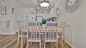 Un comedor con una mesa y sillas de madera, una lámpara colgante y un espejo decorativo en la pared.