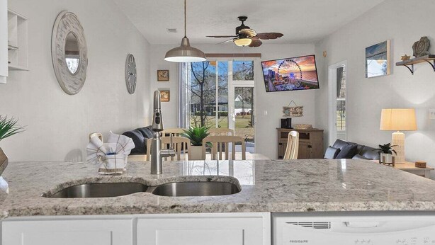 Una cocina moderna con un lavamanos doble, lavavajillas integrado y una zona de comedor con mesa y sillas.