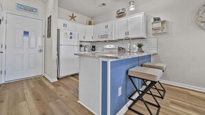 Una cocina moderna con armarios blancos, una isla azul y un refrigerador de acero inoxidable.