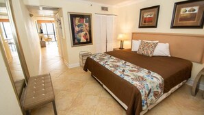 Una habitación de hotel con cama, una silla, un cuadro y una lámpara.