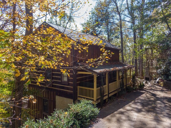 A rustic cabin with a porch, surrounded by trees and a stone fireplace. - Appalachian Seasons - Hot tub, fire place, seasonal views (Banner Elk)