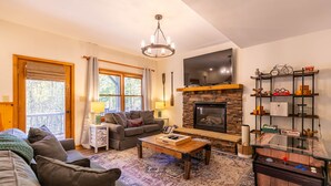 Una sala de estar acogedora con chimenea, un sofá, una mesa de centro y un televisor.
