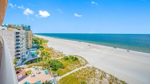 A beach view with a resort building, a pool area, and a clear sky. - 🌸CBC 1-9F -Gulf front condo with amazing views and a heated Pool! (Clearwater Beach)