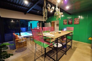 Comedor con vista a la piscina, paredes verdes y decoración moderna.