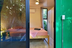 A bedroom with a bed, a window, and a green door.