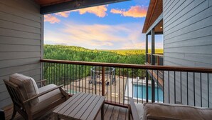 A wooden deck with a view of a forest and a swimming pool. - The Unicorn - Featured on Staycation: Luxury Broken Bow Retreat (Broken Bow)