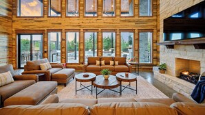 A spacious living room with a fireplace, large windows, and a cozy seating area. - The Unicorn - Featured on Staycation: Luxury Broken Bow Retreat (Broken Bow)