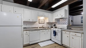 Una cocina con armarios blancos, estufa y lavamanos.