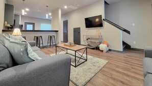 A modern living room with a sofa, coffee table, and a TV mounted on the wall.