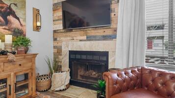 A living room with a fireplace, a mounted TV, and a leather sofa.