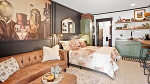 Quarto com um grande mural temático de Star Wars, um sofá estofado, uma cama com roupa de cama floral e um canto de cozinha.