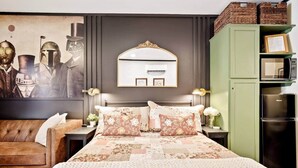 Quarto com uma cama grande, um guarda-roupa verde, um espelho fixado na parede e uma obra de arte com tema Star Wars.