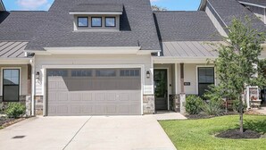 Une maison à deux étages avec un grand portail de garage, un petit garage attenant et un porche avant couvert.