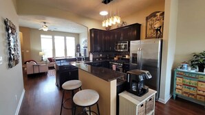 A modern kitchen with dark wood cabinets, a stainless steel refrigerator, a coffee maker, and a bar stool.