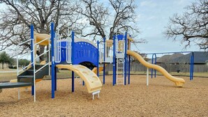 A playground with a slide, climbing structures, and a covered area.