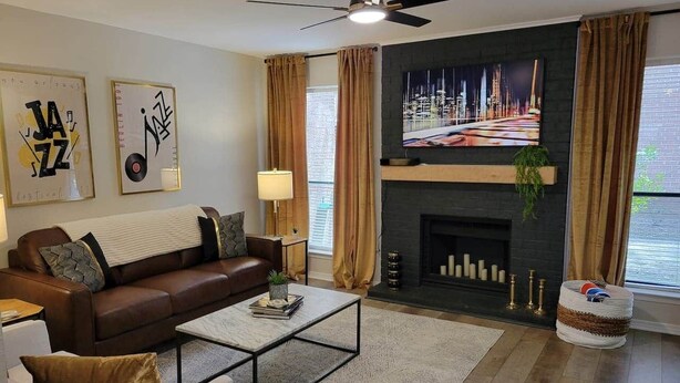 A modern living room with a fireplace, a sofa, a coffee table, and artwork on the wall. - Jazz Houzz @ Aggieland (College Station)