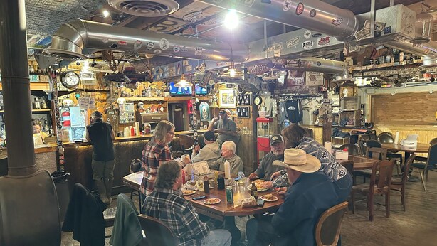 A restaurant with a rustic interior, wooden tables, and a variety of items on the walls.