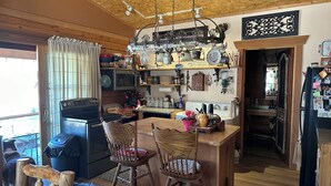 A rustic kitchen with wooden beams, a built-in oven, and a bar area with chairs.