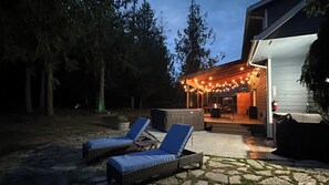 An outdoor patio area with lounge chairs and a covered seating area with string lights.