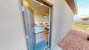 A hotel room with a bed, bedside table, and a small window. - Private Suite Near Lake Powell | Antelope Canyon (Page)