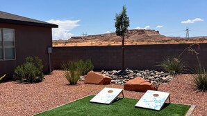 A backyard with artificial grass, two lawn chairs, a small table, and a potted plant. - Private Suite Near Lake Powell | Antelope Canyon (Page)